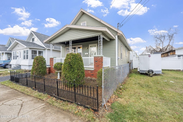 bungalow featuring covered porch and a front yard