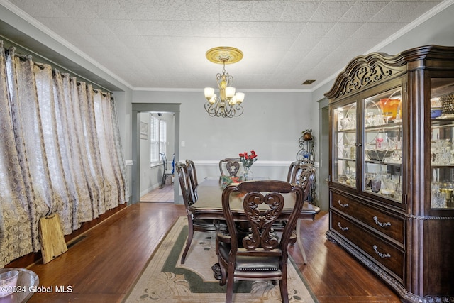 dining room featuring a notable chandelier, dark hardwood / wood-style flooring, and crown molding