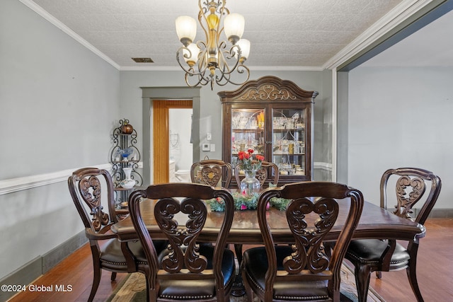 dining room with wood-type flooring, crown molding, and an inviting chandelier