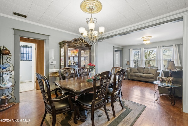 dining space featuring dark hardwood / wood-style floors, an inviting chandelier, and ornamental molding