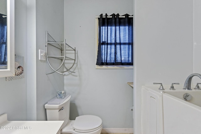 bathroom featuring a washtub, toilet, and vanity