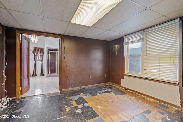 unfurnished room with a paneled ceiling and tile patterned floors