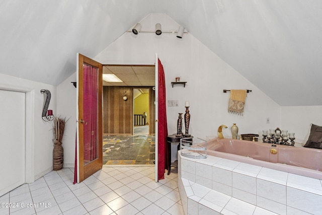 bathroom featuring tile patterned floors, tiled bath, and vaulted ceiling