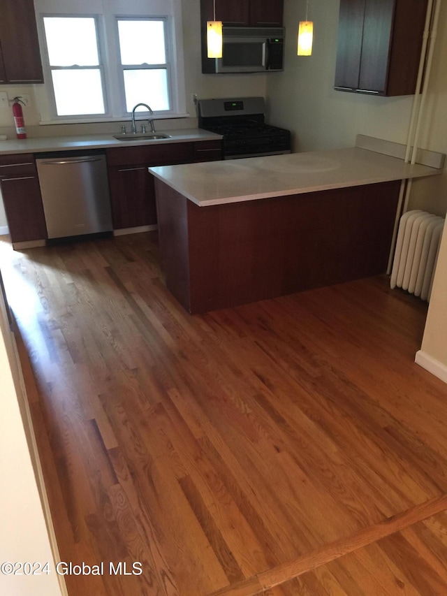 kitchen with radiator, dark brown cabinetry, hanging light fixtures, stainless steel appliances, and dark hardwood / wood-style floors