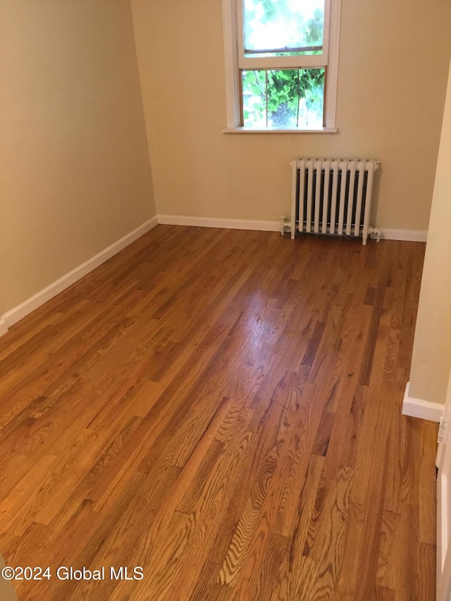 empty room with wood-type flooring and radiator