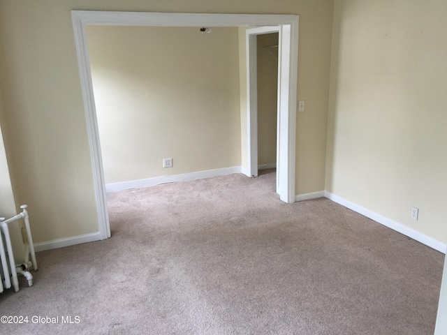 carpeted empty room featuring radiator heating unit