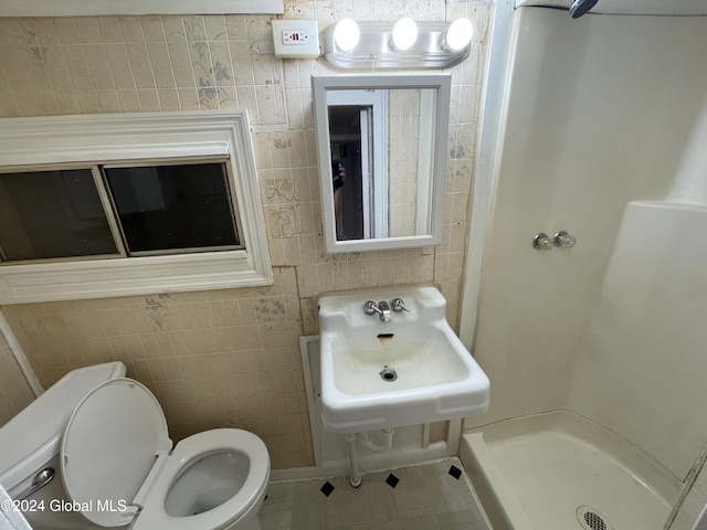 bathroom featuring walk in shower, sink, tile walls, and toilet