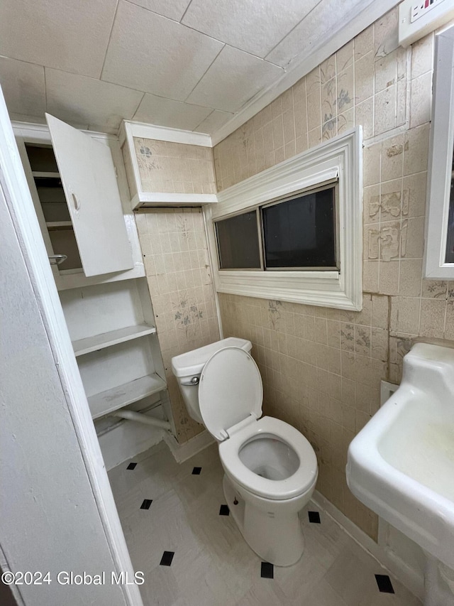 bathroom featuring sink, tile walls, and toilet