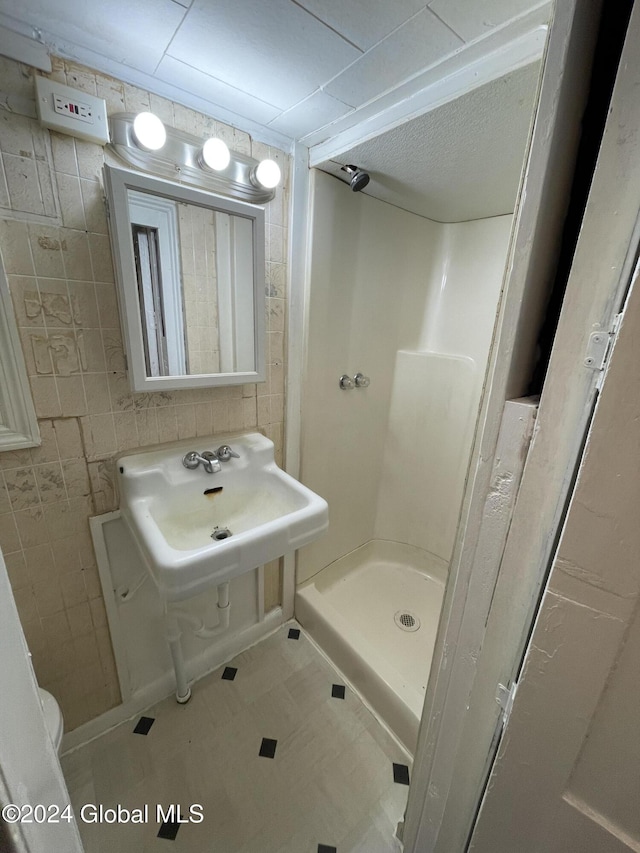 bathroom featuring tile walls, sink, and walk in shower