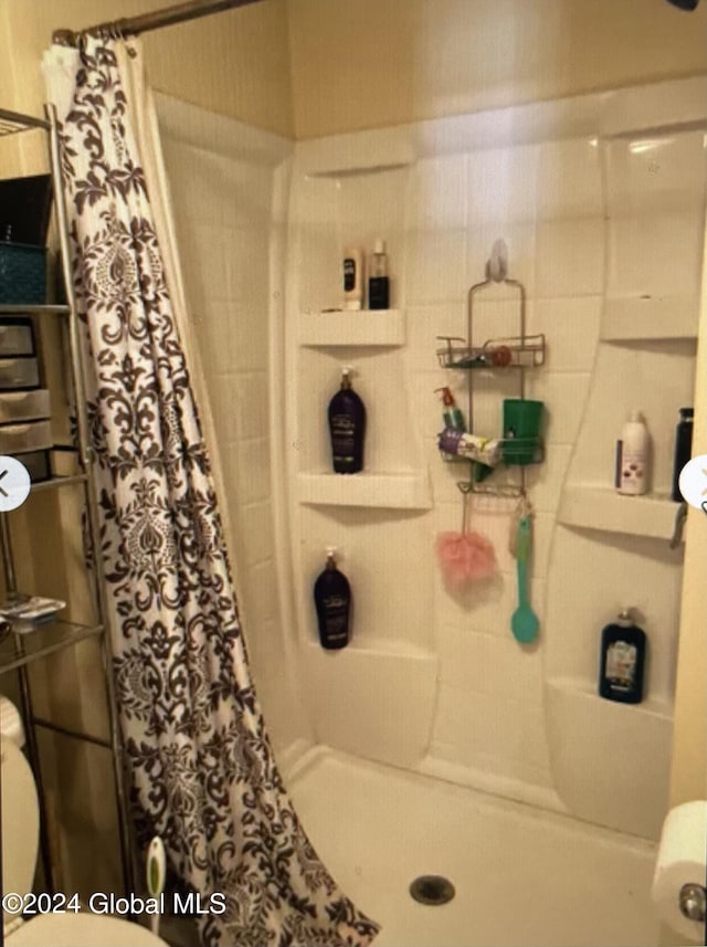 bathroom featuring toilet and curtained shower