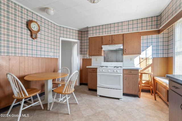 kitchen with white gas range and wood walls