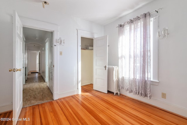 unfurnished bedroom with radiator heating unit and wood-type flooring