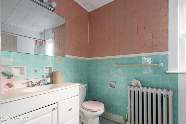 bathroom featuring vanity, toilet, tile walls, and radiator