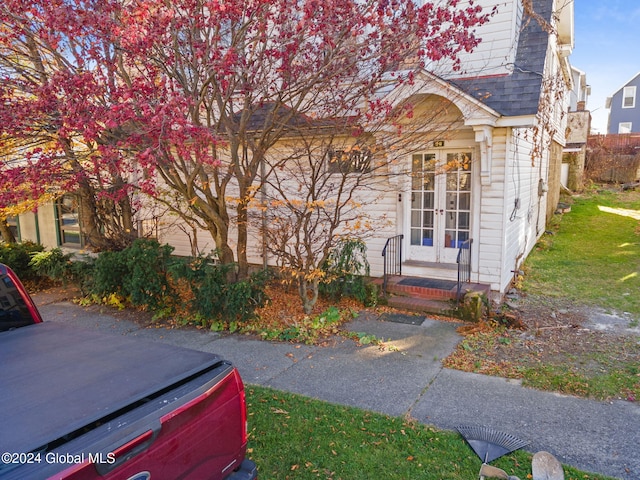 view of property hidden behind natural elements with french doors