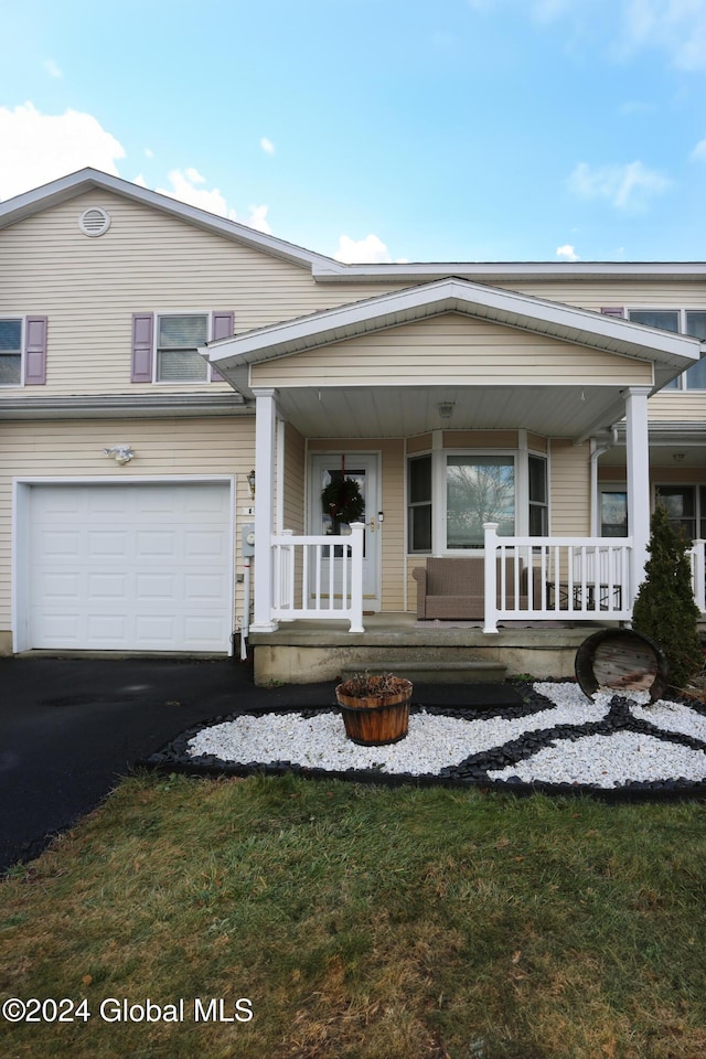 view of front of property with covered porch, a front yard, and a garage