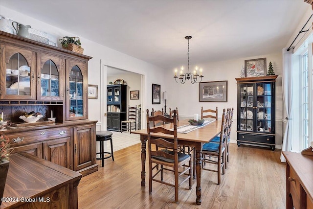 dining space with light wood-type flooring and a notable chandelier