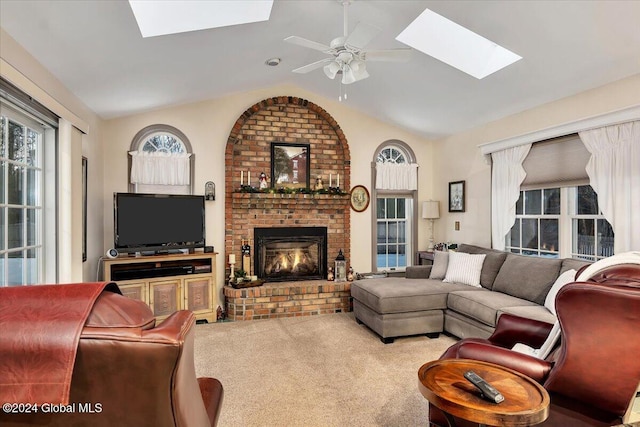 living room with carpet flooring, a fireplace, ceiling fan, and vaulted ceiling with skylight