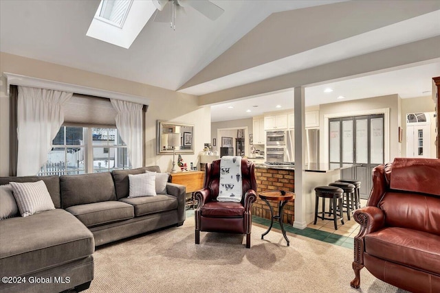 carpeted living room featuring lofted ceiling with skylight and ceiling fan