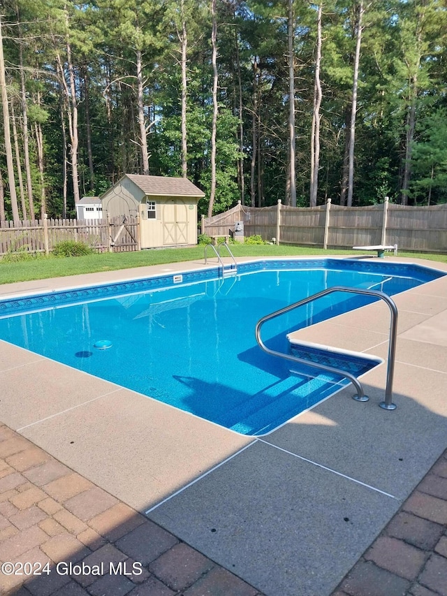 view of pool featuring a storage unit and a diving board