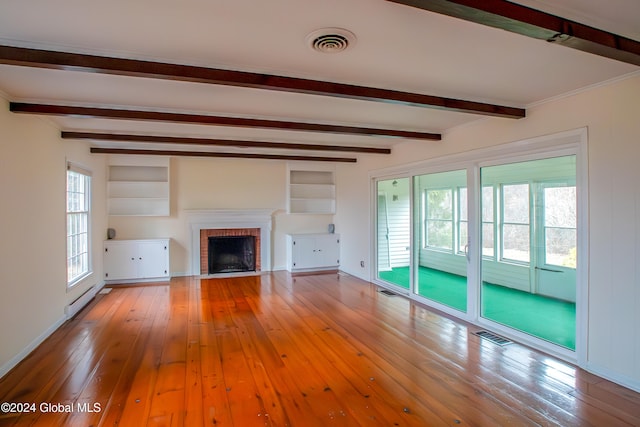 unfurnished living room with a fireplace, beamed ceiling, and light hardwood / wood-style floors