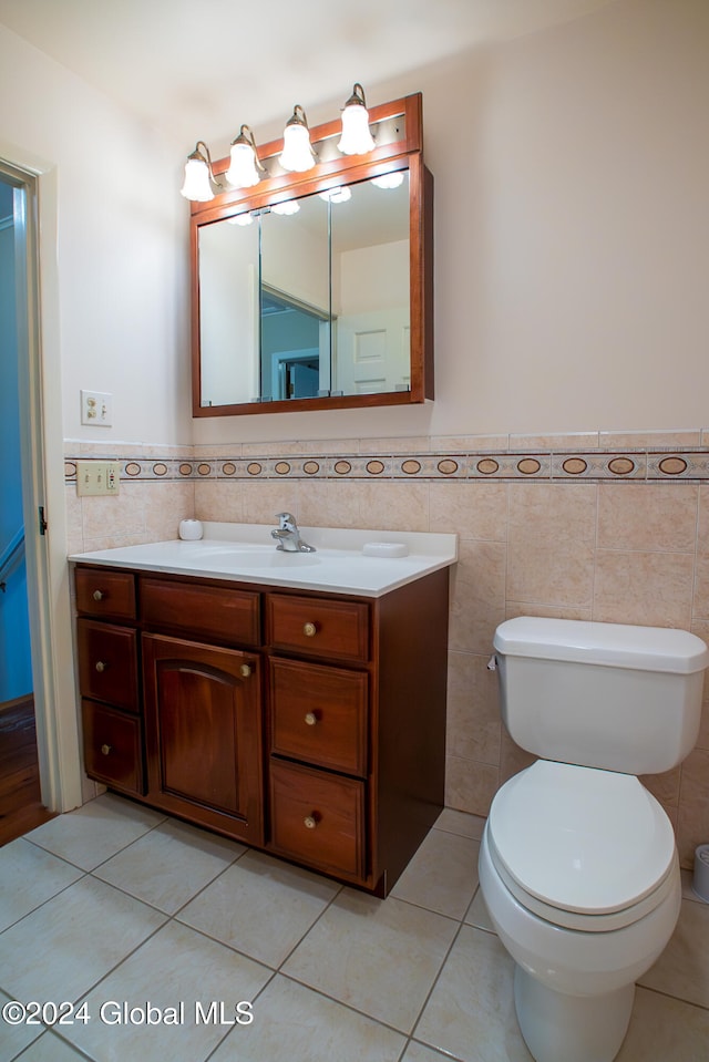 bathroom featuring toilet, vanity, tile patterned floors, and tile walls