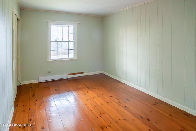 unfurnished room featuring hardwood / wood-style floors and a baseboard heating unit