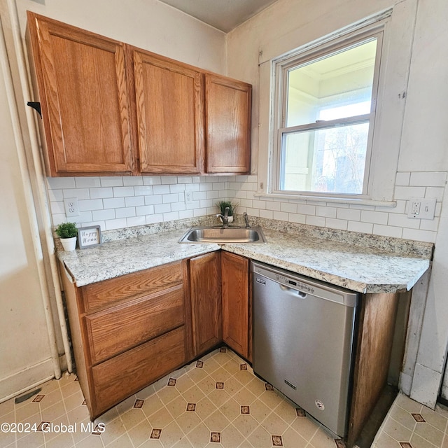 kitchen featuring dishwasher, tasteful backsplash, light stone counters, and sink