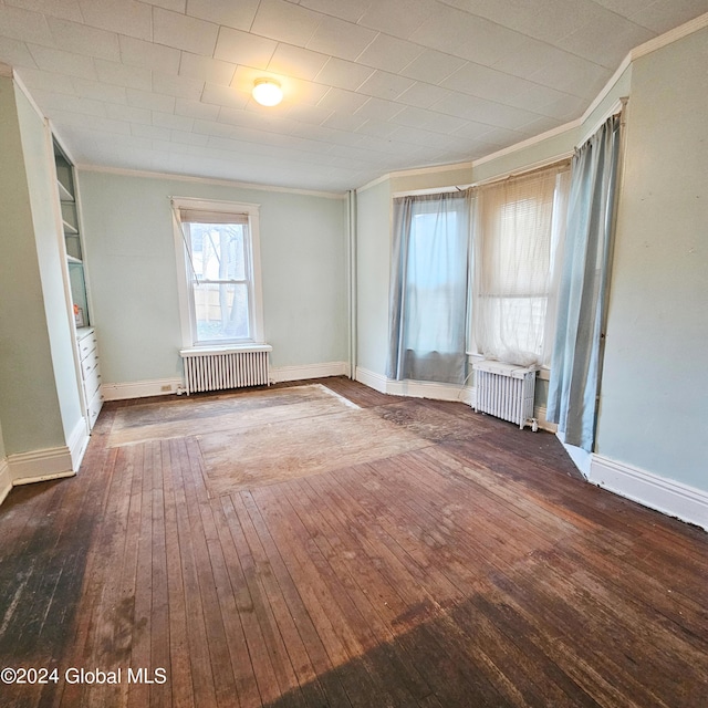 spare room with built in shelves, radiator heating unit, wood-type flooring, and ornamental molding