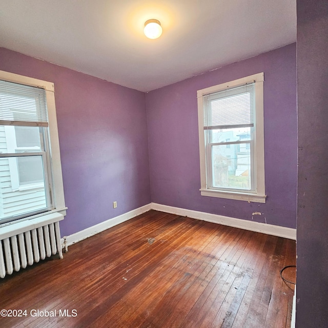 unfurnished room featuring radiator heating unit and hardwood / wood-style floors