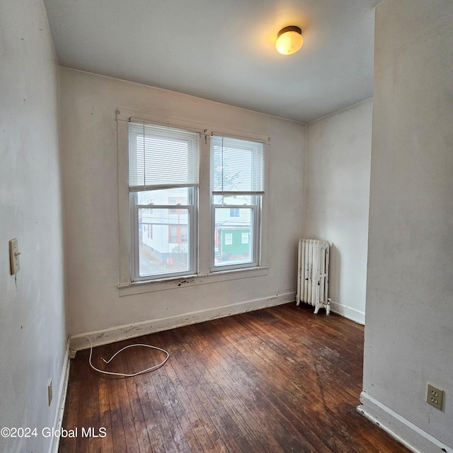 spare room with dark wood-type flooring and radiator