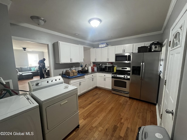 kitchen featuring stainless steel appliances, crown molding, white cabinets, washing machine and dryer, and dark hardwood / wood-style floors