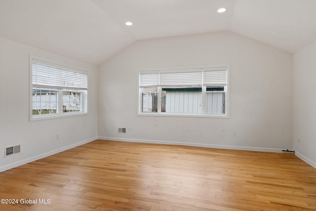 unfurnished room featuring lofted ceiling and light hardwood / wood-style flooring