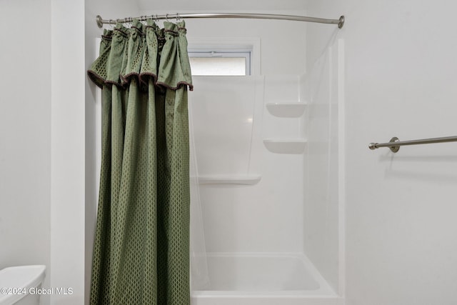 bathroom featuring a shower with curtain and toilet