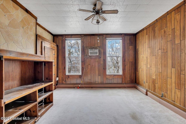 interior space featuring an AC wall unit, ceiling fan, light colored carpet, and wood walls