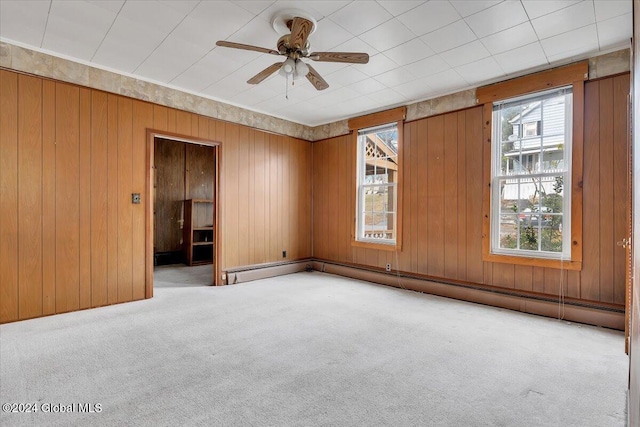 unfurnished room with light carpet, ceiling fan, and wood walls