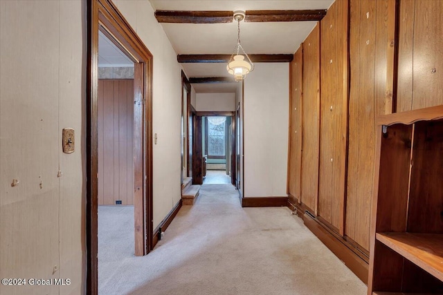 hall with light carpet, beam ceiling, and wooden walls