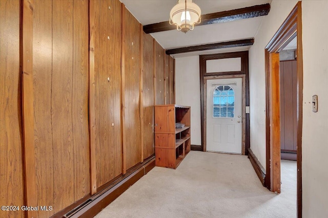 hall featuring wood walls, beamed ceiling, and light colored carpet