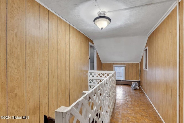 hallway featuring lofted ceiling, a textured ceiling, wooden walls, and light parquet flooring