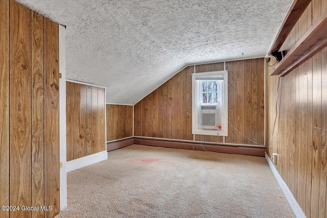 additional living space featuring carpet, a textured ceiling, wooden walls, and lofted ceiling