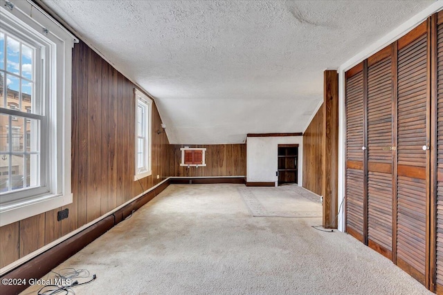 bonus room featuring a textured ceiling, light colored carpet, a healthy amount of sunlight, and lofted ceiling