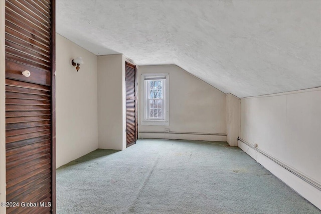 additional living space featuring baseboard heating, a textured ceiling, carpet floors, and vaulted ceiling