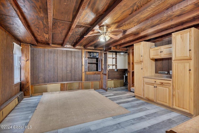 interior space featuring wooden walls, beamed ceiling, and light wood-type flooring