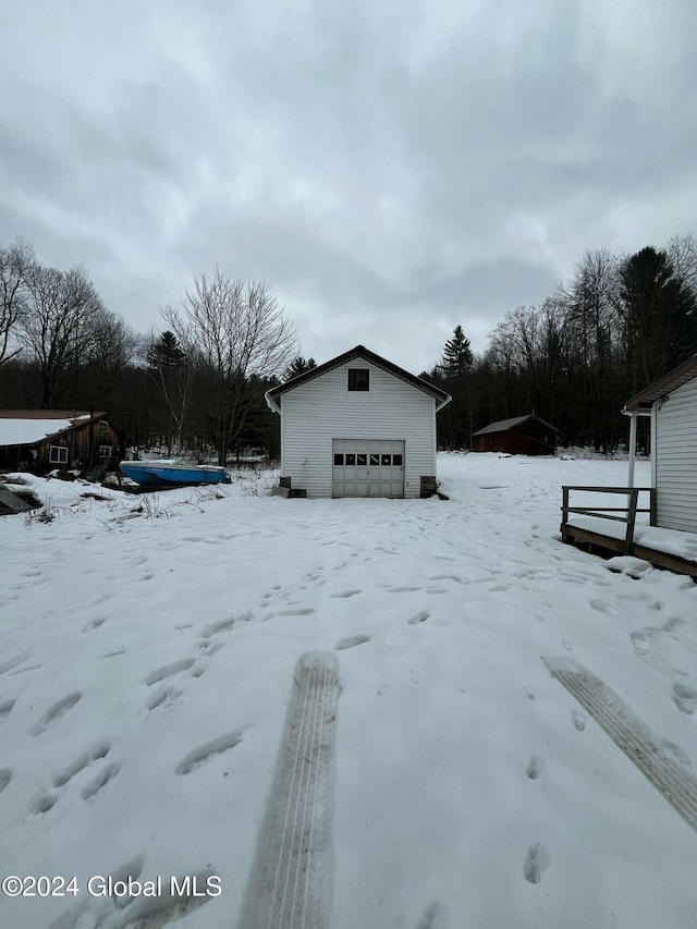 yard layered in snow featuring a garage and an outdoor structure