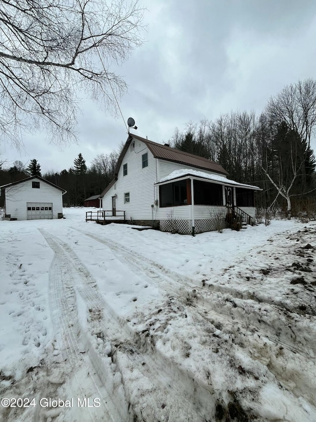 view of snowy exterior with an outdoor structure and a garage