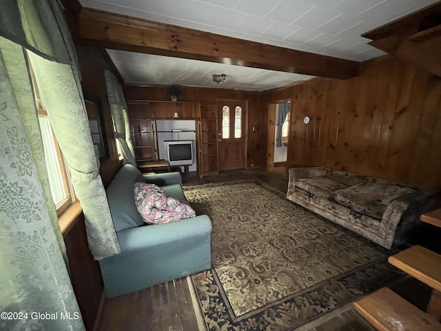 living room with beamed ceiling and wood walls