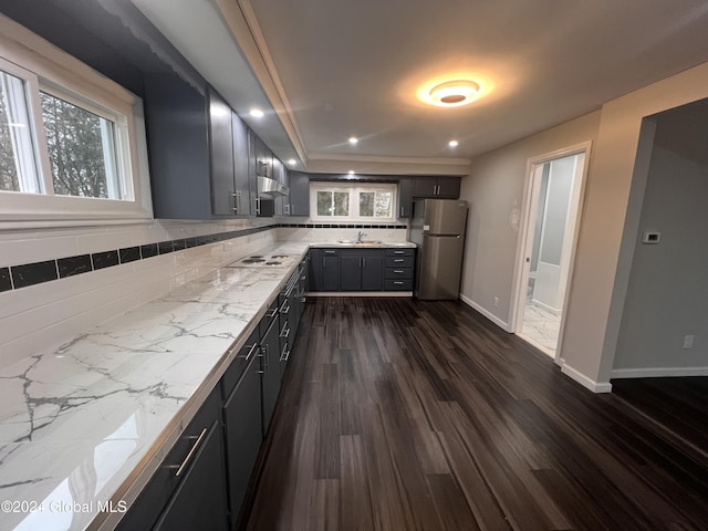 kitchen featuring gray cabinetry, white gas stovetop, backsplash, dark wood-type flooring, and stainless steel refrigerator