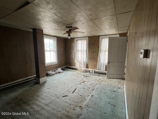 miscellaneous room featuring ceiling fan and wood walls