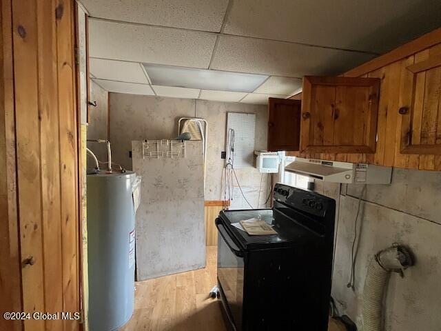 interior space with a paneled ceiling, electric water heater, ventilation hood, light hardwood / wood-style flooring, and black / electric stove