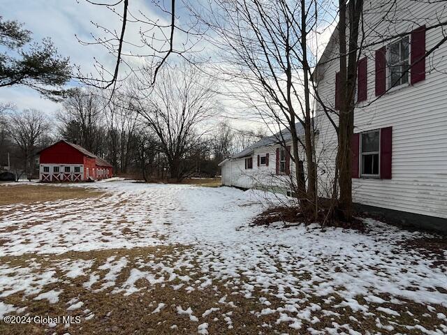 snowy yard featuring an outbuilding