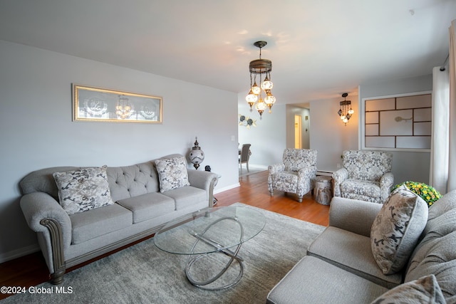 living room featuring light hardwood / wood-style flooring, a baseboard heating unit, and a notable chandelier